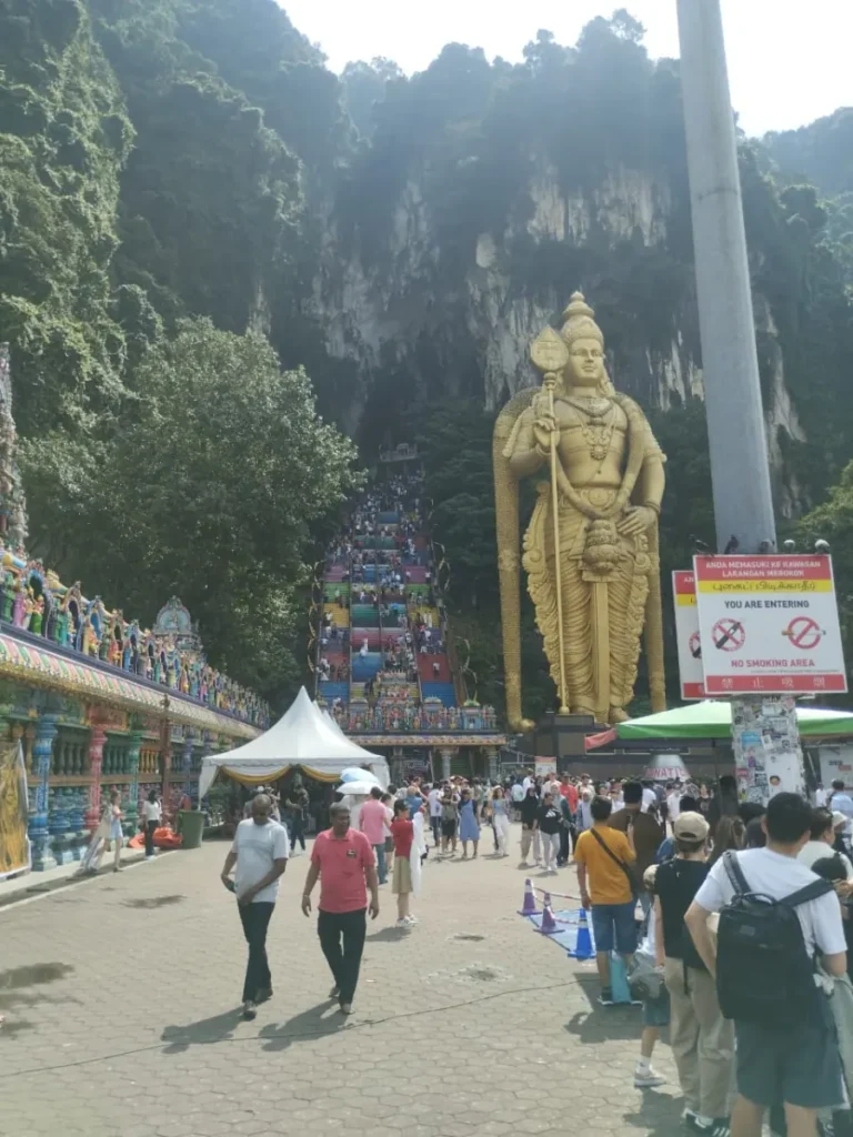 Lord Murugan statue and crowded rainbow staircase at Batu Caves