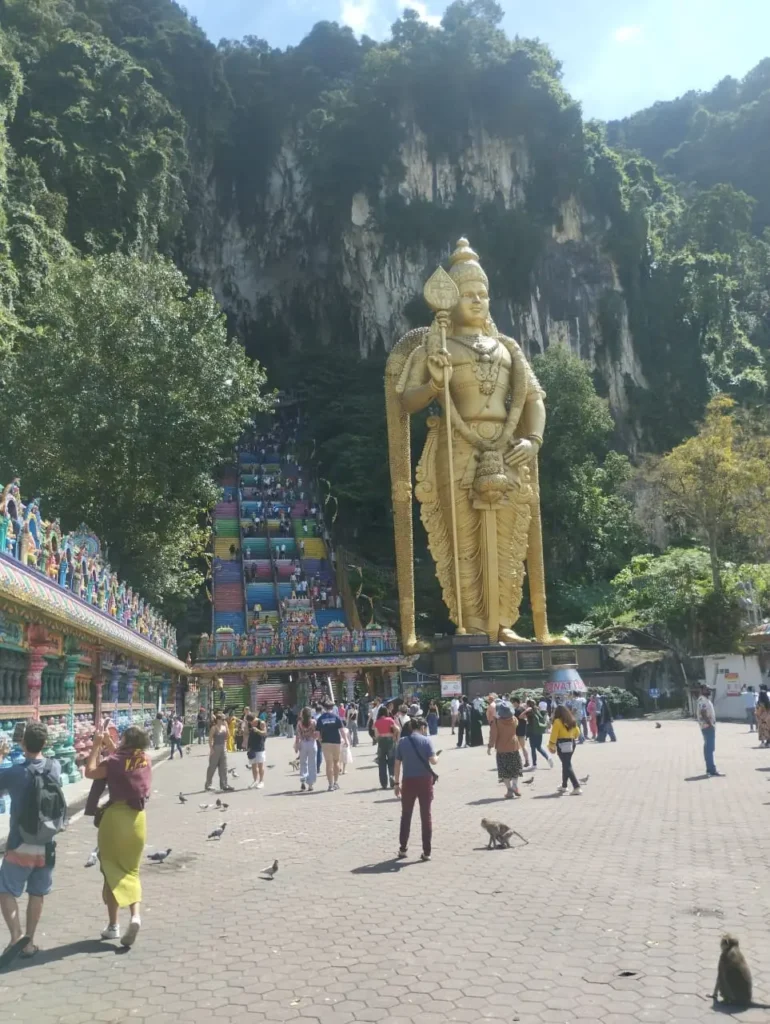 Batu Caves entrance with the Murugan statue, rainbow staircase, visitors and monkeys