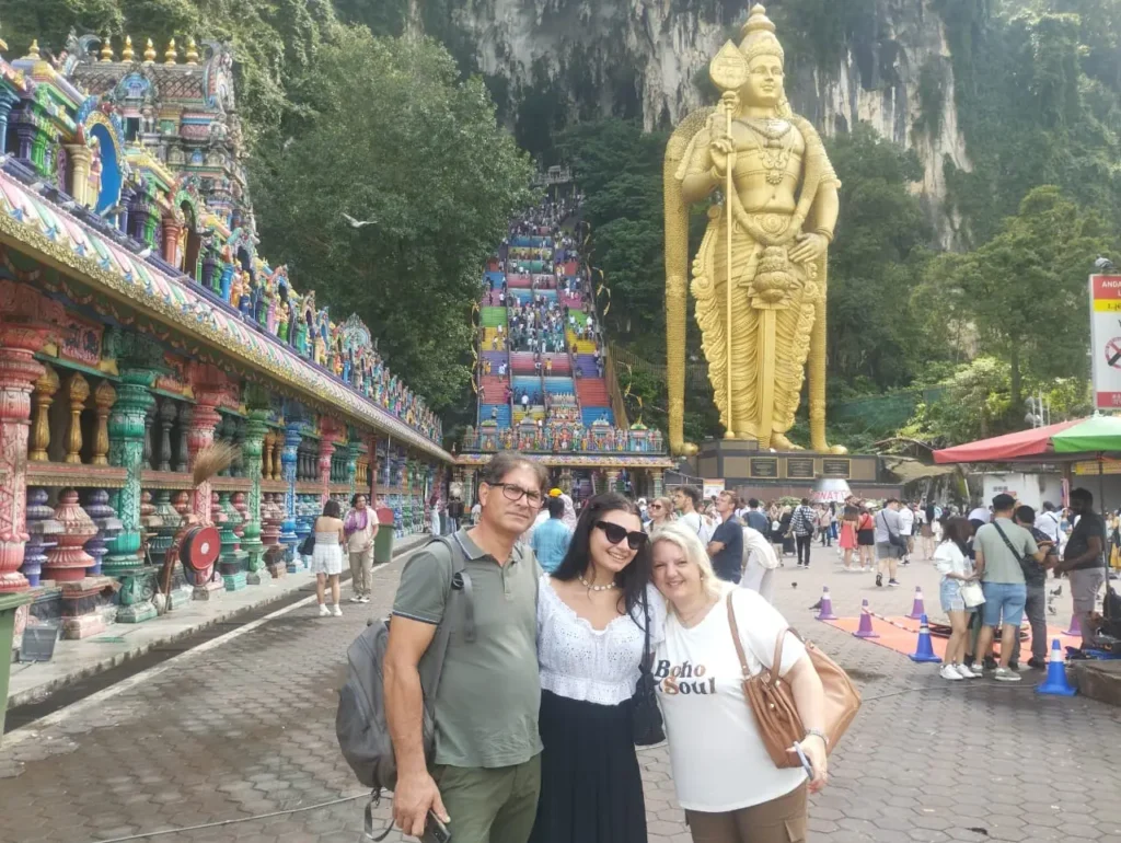 Previous SGMY Private Tours guests at Batu Caves with the Murugan statue and rainbow stairs behind them