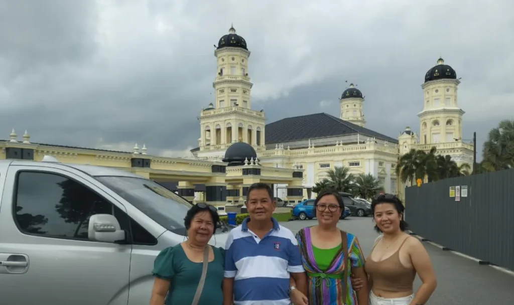 Previous private-tour guests beside an example vehicle at Sultan Abu Bakar State Mosque in Johor Bahru